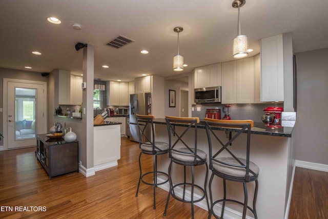 409 Celebration Rd, Knoxville, TN 37934 - kitchen with stainless steel appliances, a peninsula, wood finished floors, tasteful backsplash, and dark countertops