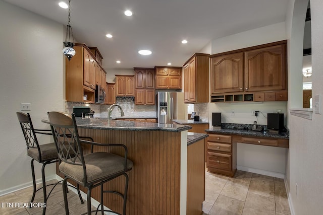 401 Shawnee Pl, Loudon, TN 37774 - kitchen with a peninsula, stainless steel appliances, a kitchen breakfast bar, brown cabinetry, and dark stone countertops