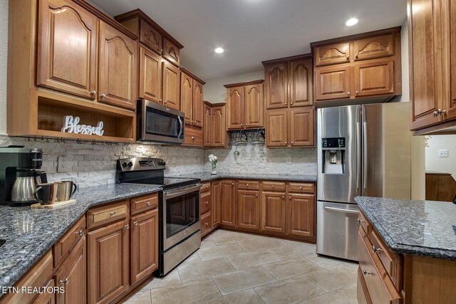 401 Shawnee Pl, Loudon, TN 37774 - kitchen with appliances with stainless steel finishes, light tile patterned flooring, brown cabinetry, tasteful backsplash, and dark stone countertops
