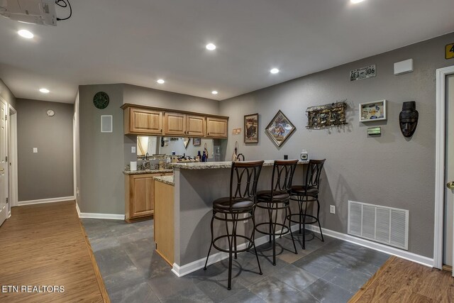 401 Shawnee Pl, Loudon, TN 37774 - kitchen with a peninsula, a kitchen bar, baseboards, light stone countertops, and recessed lighting