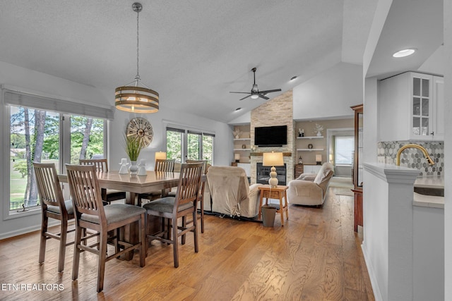 dining area featuring plenty of natural light, light wood-style flooring, a ceiling fan, built in features, and lofted ceiling