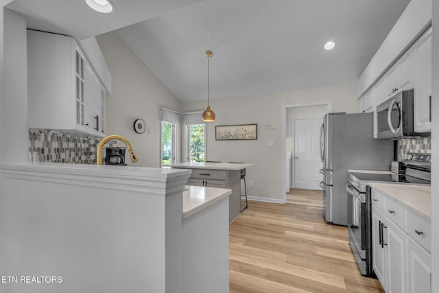 kitchen with stainless steel appliances, decorative backsplash, light wood-style floors, white cabinetry, and glass insert cabinets