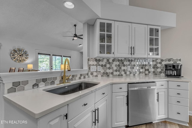 kitchen featuring dishwasher, a sink, ceiling fan, decorative backsplash, and white cabinetry