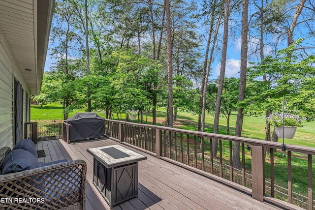 wooden terrace featuring a grill, view of scattered trees, and a yard