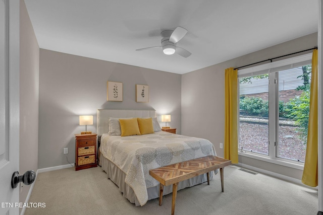 bedroom featuring light colored carpet, baseboards, and ceiling fan