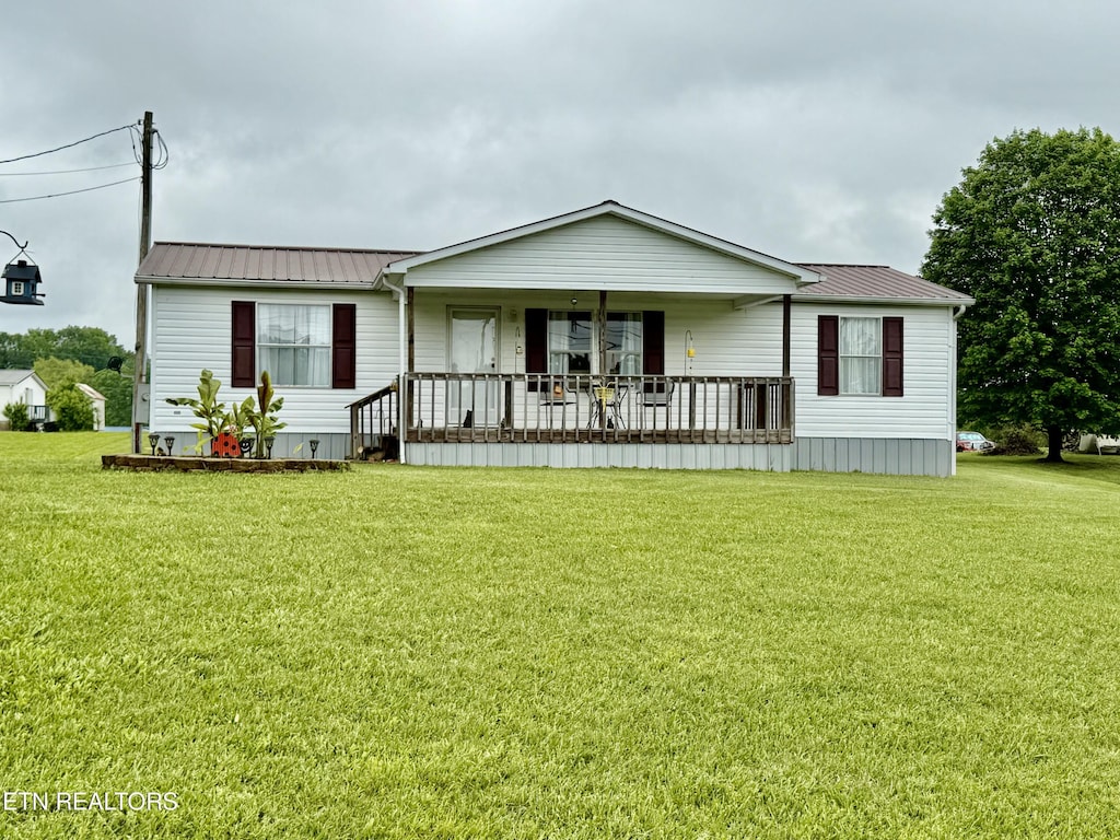 back of house with a porch, a yard, and metal roof