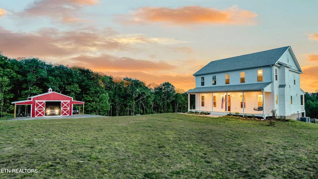 819 NW Morgan Rd, Charleston, TN 37310 - yard at dusk with covered porch, a lawn, an outbuilding, and central AC