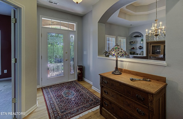 foyer entrance with arched walkways, light wood-style flooring, and healthy amount of natural light