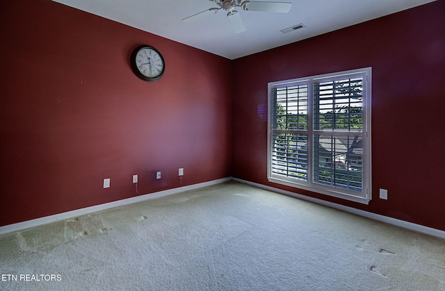 carpeted spare room featuring baseboards and ceiling fan