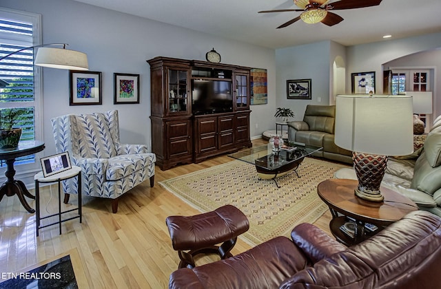 living area featuring arched walkways, ceiling fan, light wood-style floors, and recessed lighting