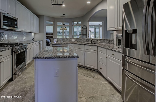 kitchen with stainless steel appliances, a sink, decorative backsplash, a peninsula, and recessed lighting