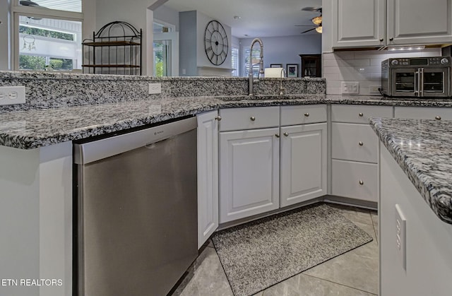 kitchen featuring stainless steel dishwasher, a sink, white cabinetry, ceiling fan, and plenty of natural light