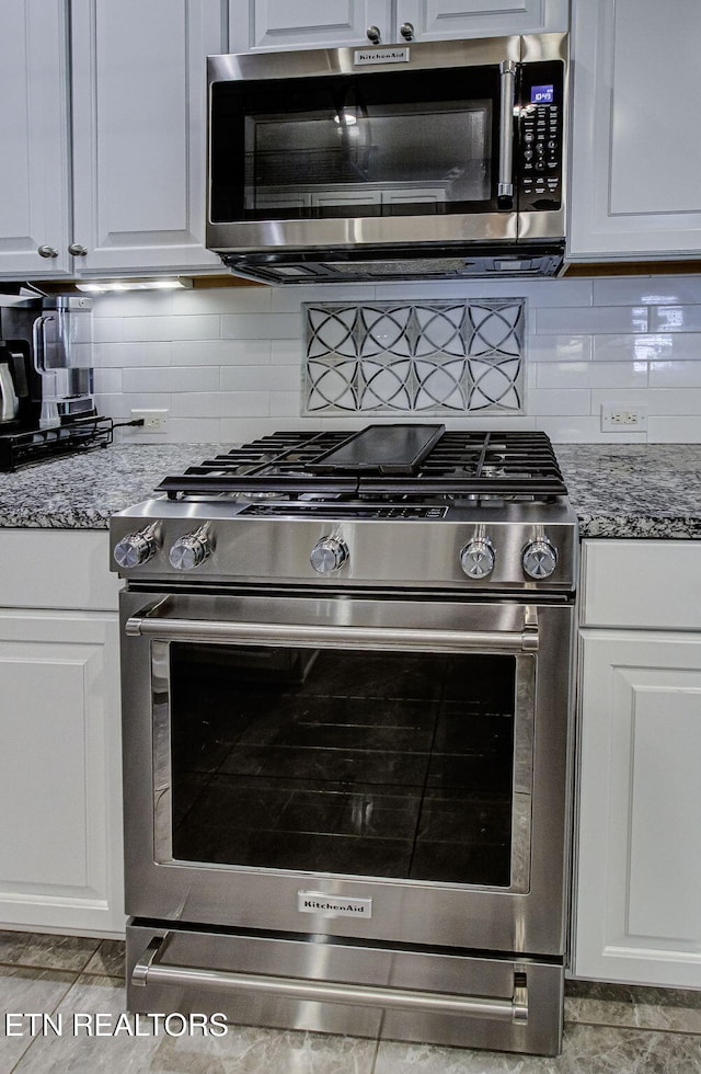 kitchen with appliances with stainless steel finishes, backsplash, and white cabinetry