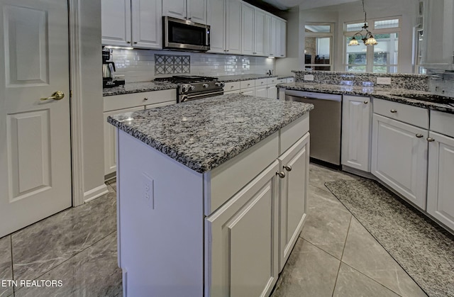 kitchen with stainless steel appliances, a center island, backsplash, and white cabinetry
