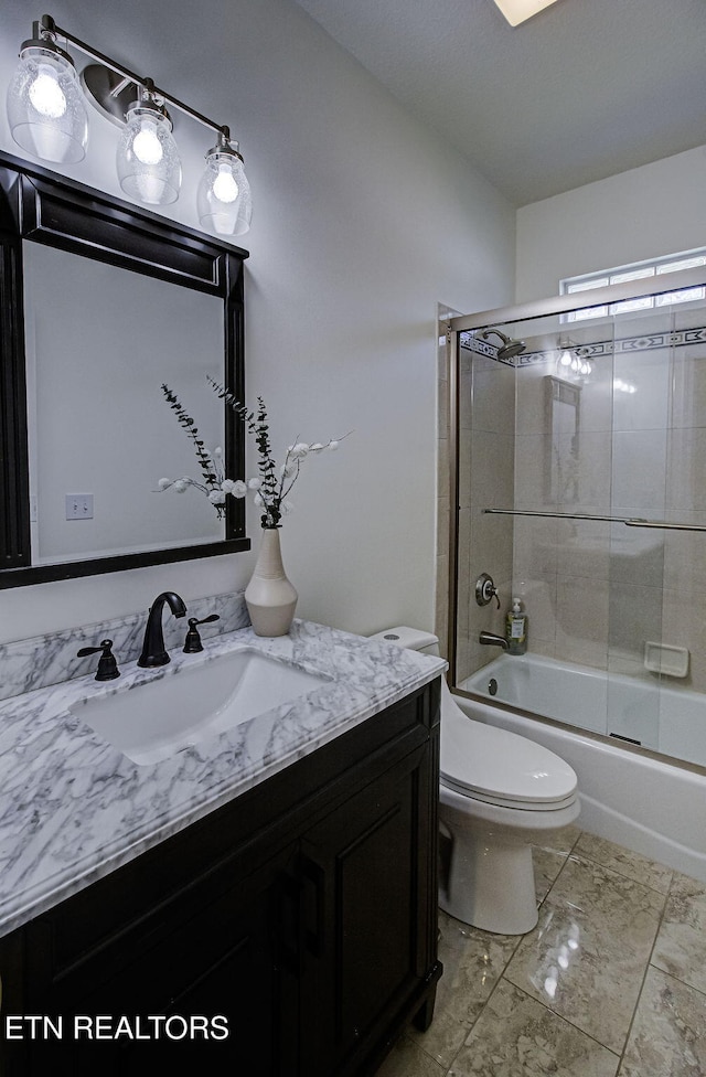 full bath with marble look tile flooring, toilet, vanity, and bath / shower combo with glass door