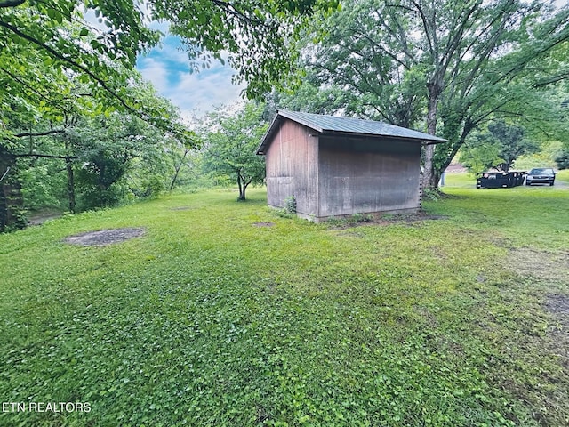view of green lawn featuring a storage shed and an outbuilding