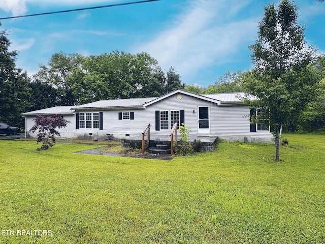 rear view of house featuring a yard and metal roof