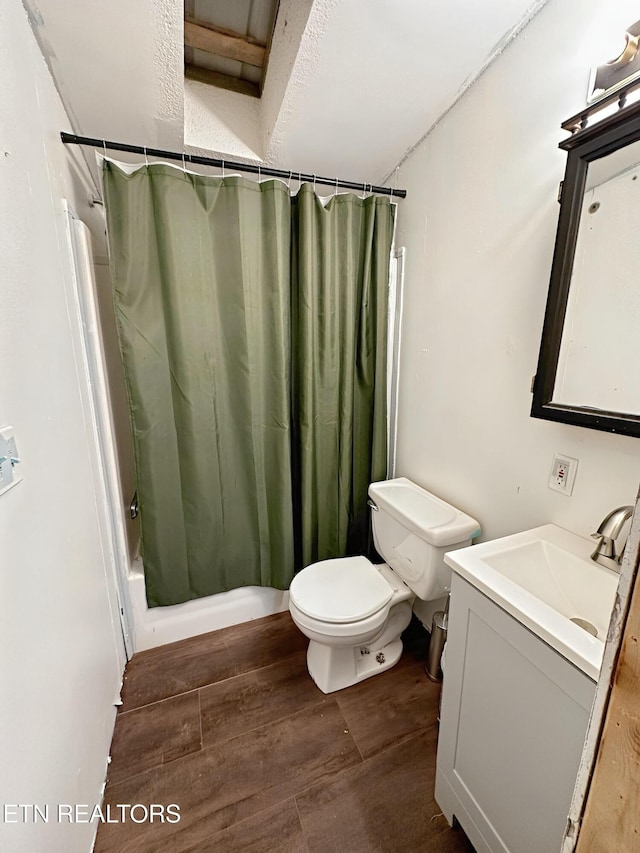 bathroom with toilet, wood finished floors, and vanity