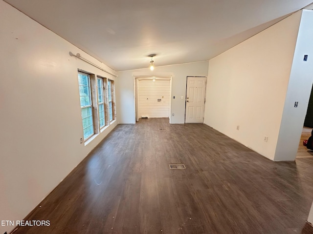 spare room with dark wood finished floors and lofted ceiling