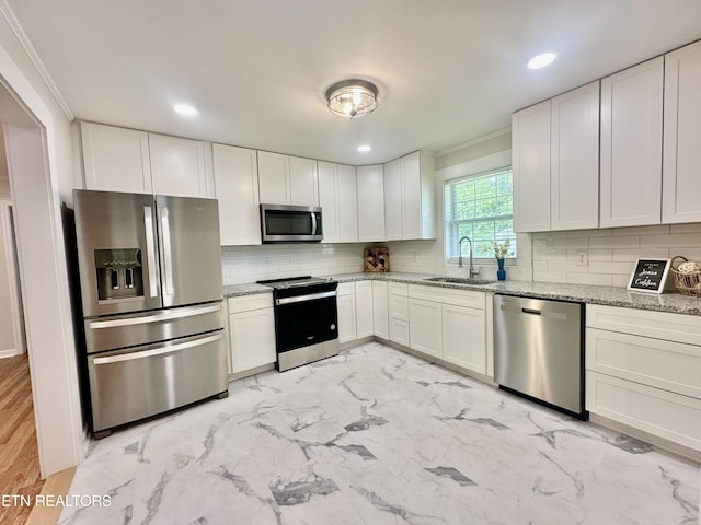 kitchen featuring appliances with stainless steel finishes, a sink, tasteful backsplash, white cabinets, and recessed lighting