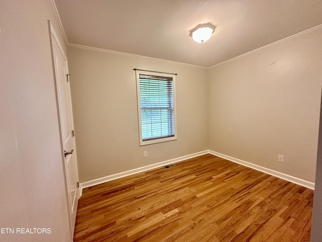 spare room with ornamental molding, wood finished floors, and baseboards