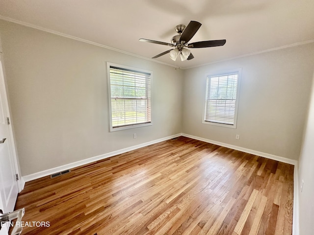 spare room with ornamental molding, plenty of natural light, wood finished floors, baseboards, and a ceiling fan