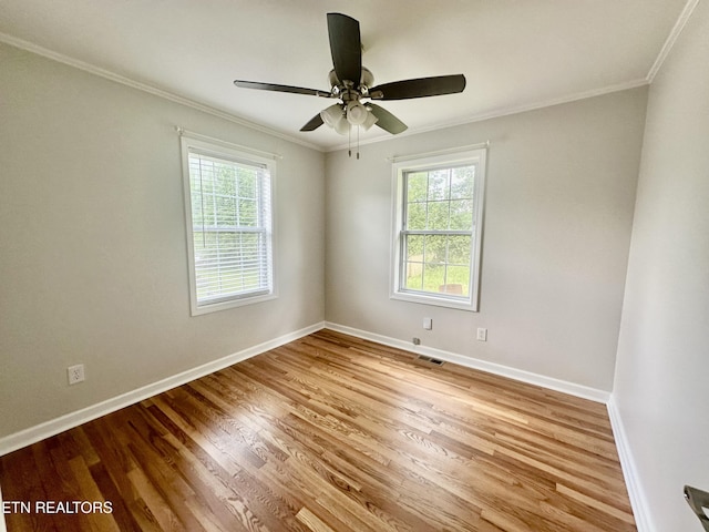empty room featuring plenty of natural light, ornamental molding, baseboards, and wood finished floors