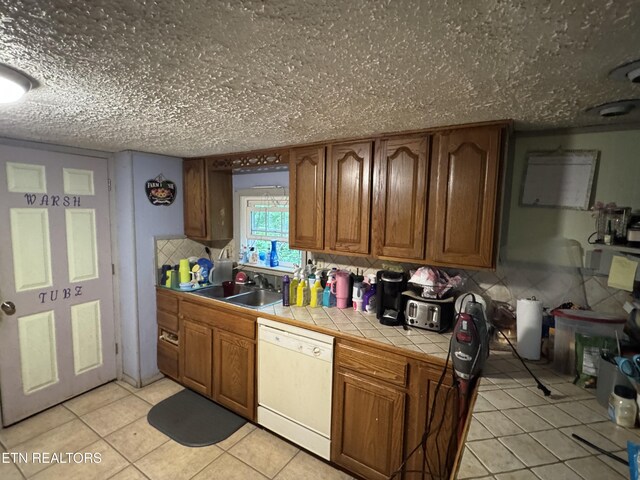 3441 Glendale Rd, Bybee, TN 37713 - kitchen with white dishwasher, tile counters, a sink, light tile patterned floors, and brown cabinetry