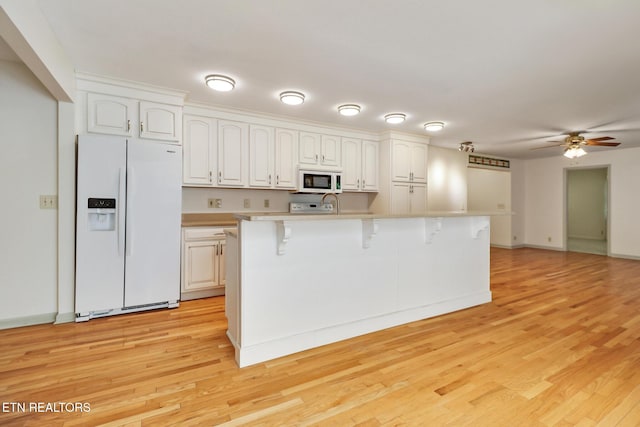 11 Kingsboro Ln, Crossville, TN 38558 - kitchen featuring white appliances, a breakfast bar, a ceiling fan, white cabinets, and light wood-style floors