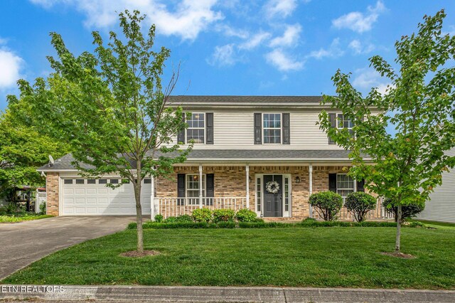 traditional-style home with driveway, covered porch, a front lawn, a garage, and brick siding