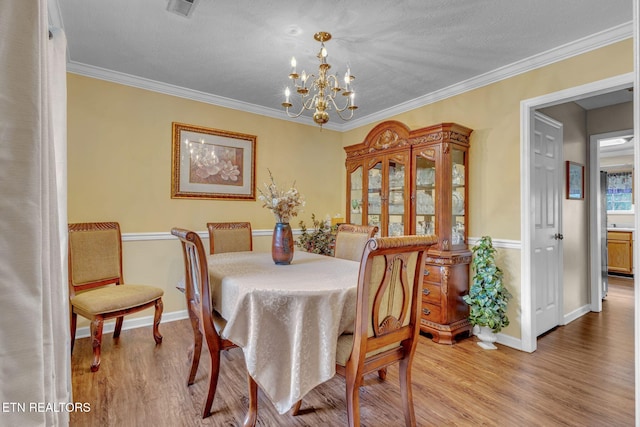 dining area featuring a chandelier, wood finished floors, baseboards, and crown molding