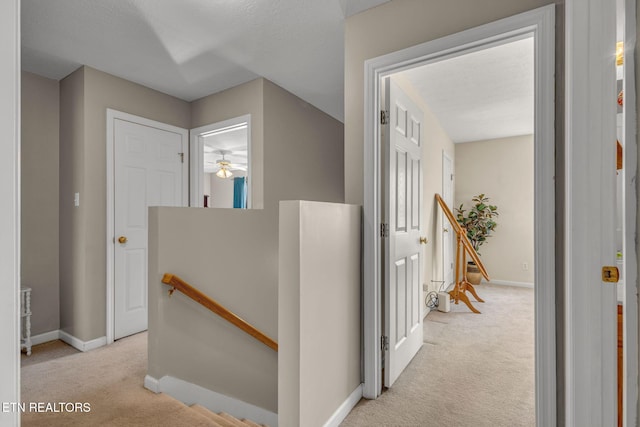 hall with an upstairs landing, carpet, and baseboards