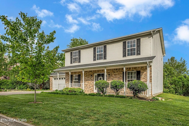 traditional home featuring a porch, a front yard, driveway, an attached garage, and brick siding