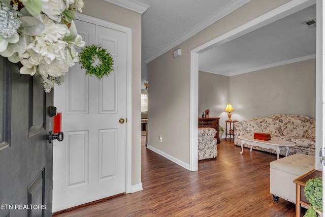entryway with wood finished floors, ornamental molding, and baseboards