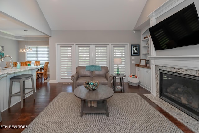 109 Niwodihi Trl, Vonore, TN 37885 - living room with lofted ceiling, a fireplace, dark wood-style floors, a chandelier, and baseboards