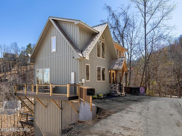view of side of home with board and batten siding, stairway, a wooden deck, and metal roof