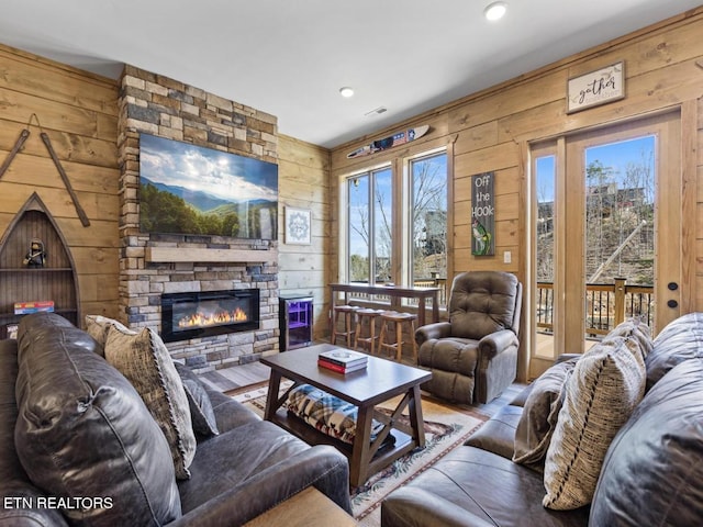 living room featuring wooden walls, a stone fireplace, wood finished floors, and recessed lighting