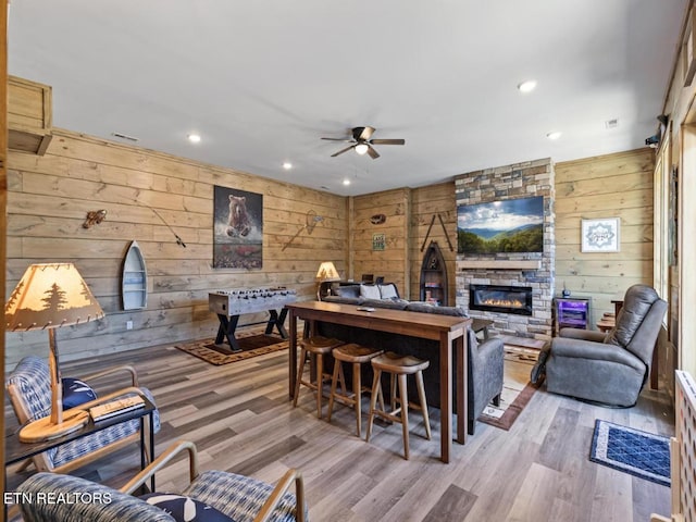 living room with wood walls, a ceiling fan, a fireplace, wood finished floors, and recessed lighting