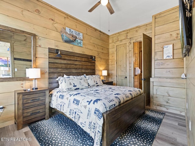 bedroom featuring wood walls, wood finished floors, and ceiling fan