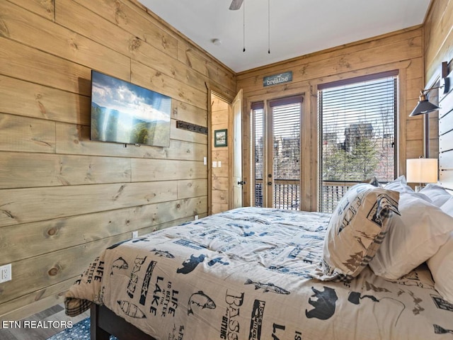 bedroom with wood walls, access to exterior, and ceiling fan