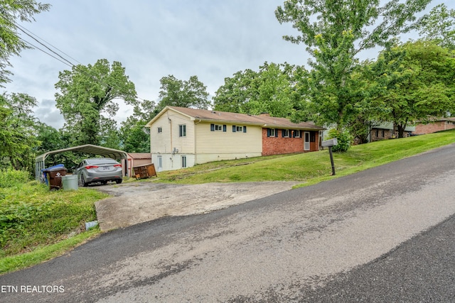 view of front facade with a detached carport, asphalt driveway, a front yard, and brick siding