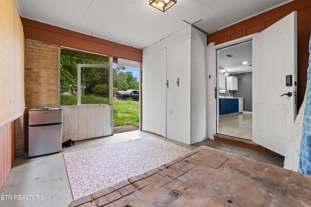 doorway featuring unfinished concrete flooring and brick wall