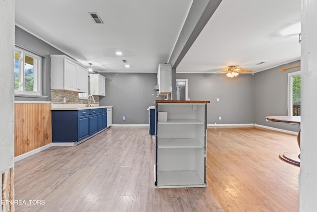 kitchen with blue cabinetry, light wood finished floors, a ceiling fan, light countertops, and open shelves