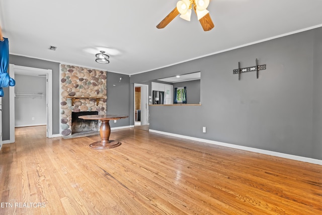 unfurnished living room featuring crown molding, a fireplace, ceiling fan, wood finished floors, and baseboards