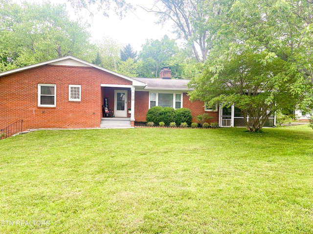 back of property with brick siding, a chimney, and a yard