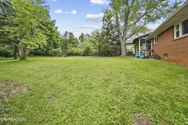 view of green lawn featuring a sunroom