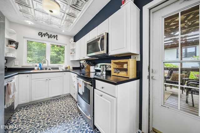 kitchen featuring stainless steel appliances, open shelves, a sink, an ornate ceiling, and dark countertops