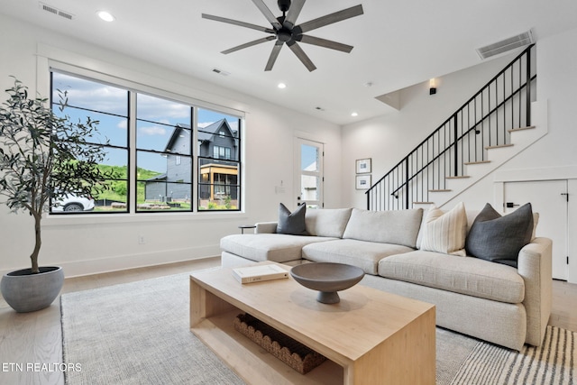 living area with ceiling fan, wood finished floors, baseboards, recessed lighting, and stairway