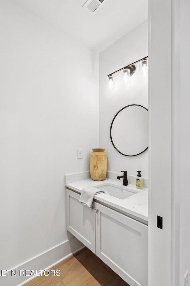 bathroom featuring vanity, wood finished floors, and baseboards