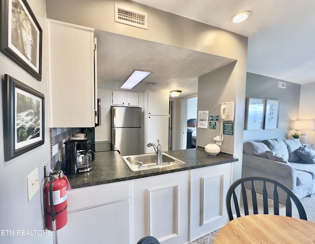 kitchen with freestanding refrigerator, a sink, dark countertops, and open floor plan